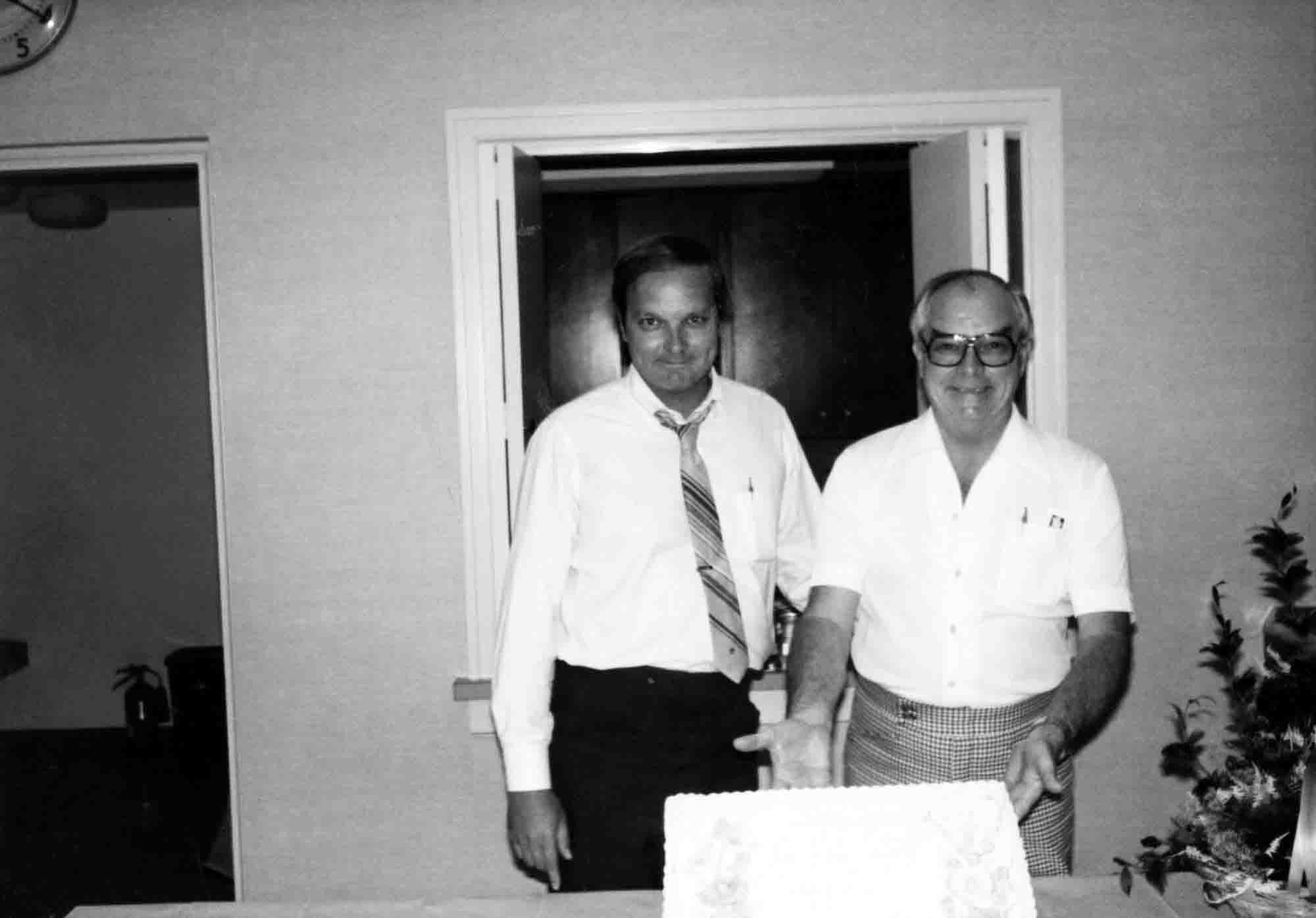 Bob McNichols and his son, Gene, smiling for a photo with cake.