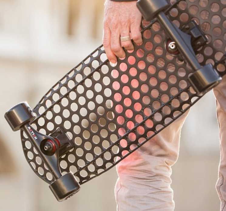 A picture of someone holding a skateboard that was made out of Perforated Metal and painted black.