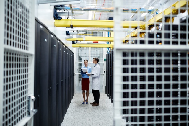 IT Specialists standing in an enclosure in a data center, surrounded by Wire Mesh.